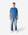 A model wearing a blue Gildan Softstyle adult T-shirt paired with light blue jeans and white shoes.