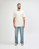 A white Gildan Softstyle adult T-shirt displayed on a model, paired with light blue jeans. The model stands against a neutral background.