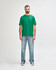 A green Gildan Softstyle adult t-shirt displayed on a male model, paired with light blue jeans.
