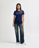 A navy blue ladies' T-shirt paired with light blue jeans and white sneakers. The shirt features a logo.