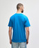 A blue midweight T-shirt viewed from the back, worn by a person with dark hair and casual pants.