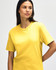 A yellow Gildan Softstyle adult midweight t-shirt on a model, featuring short sleeves and a casual fit.