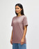 A midweight adult t-shirt in a muted pink colour, featuring a crew neckline and short sleeves. The model stands against a plain background.