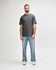A grey Gildan Softstyle midweight T-shirt displayed on a model, paired with light blue jeans and casual shoes.