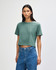 A model wearing a green boxy t-shirt, with short sleeves and loose fit, paired with light denim jeans.