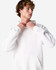 A unisex hooded sweatshirt in white, featuring a pocket and a logo on the front. The model adjusts the collar.