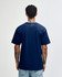 A navy blue unisex short sleeve T-shirt with a plain back, featuring a logo at the neck area.