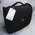 A black luggage tag attached to a stylish black bag, featuring a logo and an empty information panel.