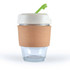 A reusable coffee cup with a cork band and a white lid featuring a green straw. The cup is made of transparent glass.