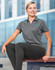 A grey polo shirt with contrast blue accents, featuring a logo, worn by a woman sitting outdoors.