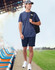A man wearing a navy blue short-sleeve performance T-shirt and navy shorts, carrying a black backpack.