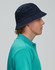 A navy blue contrasting underbrim bucket hat displayed on a model's head, featuring eyelet detailing.