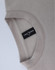 A crew neck sweater in a light beige colour, featuring a label and a soft fleecy texture.