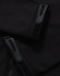 Close-up of a black softshell jacket featuring zippers and velcro details. The jacket has a logo on it.