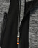 A grey and black jacket featuring a zippered front and a logo on the zipper pull.
