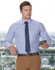 A men's long-sleeve shirt in a blue and white gingham check pattern, paired with a navy tie and beige trousers.