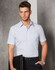 A men's short-sleeve button-up shirt in light blue, featuring a chest pocket and a logo. Styled with black trousers.