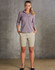 A model wearing khaki chino shorts paired with a button-up shirt, standing against a textured grey background.