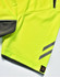 A close-up of a bright yellow polo shirt featuring grey accents and a logo on the hem.