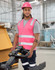 A pink hi-vis safety vest with shoulder reflective tapes, worn by a person in a warehouse setting, featuring a logo.