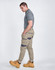 Unisex cotton stretch drill cuffed work pants in light beige with a logo, paired with a grey polo and yellow boots.