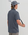A grey sustainable jacquard knit short-sleeve polo shirt, featuring a logo, worn by a person holding a golf club.