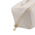 A cream toiletry bag featuring a gold zipper and a branded tag. The bag has a geometric shape and smooth finish.