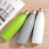 A drink bottle set featuring green, grey, and white metal bottles with stainless steel caps, placed on a wooden surface.