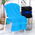 A bright blue bath towel draped over a white chair, with stacked black and blue towels beside it.