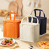 A set of three insulated lunch bags in orange, navy, and cream, with handles for easy carrying.