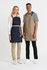 A navy bib apron on a woman and a beige bib apron on a man, both with shoulder straps, standing together.
