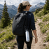 A drink bottle in silver hanging from a backpack, with a mountainous landscape in the background.