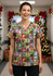 A women's Christmas scrub top featuring a colourful holiday-themed print with various festive characters.