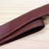 A brown faux leather strap with contrasting yellow stitching, laid flat on a wooden surface.