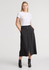 A woman wears a black midi skirt with a front slit and buttons, paired with a simple white T-shirt.