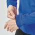 A close-up of a person's hands adjusting the sleeve of a blue long-sleeve T-shirt. The shirt has a logo.