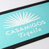 A turquoise bar runner featuring a palm leaf design and a logo, set against a black trim.