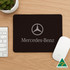 A set of three mouse mats in black, white, and grey, featuring a logo on the front of the black mat.
