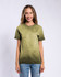 A woman stands smiling in an olive green Colortone® Oil Wash T-Shirt, paired with light blue jeans. The shirt has a branding logo.