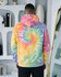 A hooded sweatshirt featuring a vibrant tie-dye pattern in pastel colours, including yellow, pink, blue, and green.