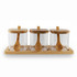 Three glass condiment jars with bamboo lids and wooden spoons, placed on a bamboo tray.