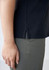 A side view of a navy women's polo shirt featuring a small slit at the hem, paired with light-coloured pants.