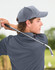 A young man wearing a grey jacquard texture 5-panel cap, holding a golf club in a lush outdoor setting.