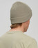 A khaki cable knit snug beanie worn by a person with short hair, viewed from the back.