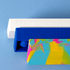 Three popper rulers in vibrant colours: a white ruler, a blue ruler, and a multicoloured patterned ruler, stacked together.