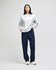 A model wearing a grey Champion Reverse Weave® adult crew sweatshirt and navy pants stands against a neutral background.
