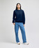A model wearing a navy blue Champion Powerblend® adult crewneck sweatshirt paired with blue jeans and white shoes.