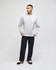 A grey adult crewneck sweatshirt displayed on a model, paired with black trousers and shoes. The sweatshirt features a logo.