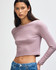 A fitted long-sleeve crop t-shirt in mauve, featuring a simple design and a logo. Styled with blue jeans.