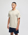 A light beige short sleeve t-shirt on a model, featuring a logo on the sleeve, paired with navy shorts.